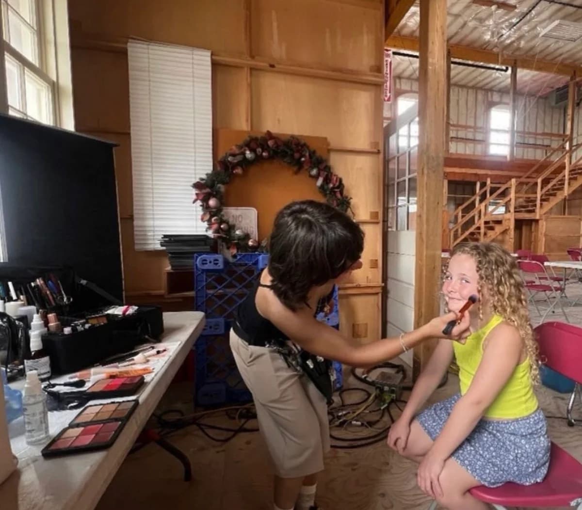 A young performer having makeup applied before filming